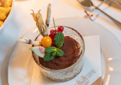 Tiramisu bedeckt mit Schokoladenpulver und Garnitur auf weissem Teller mit Porto Sofie Serviette